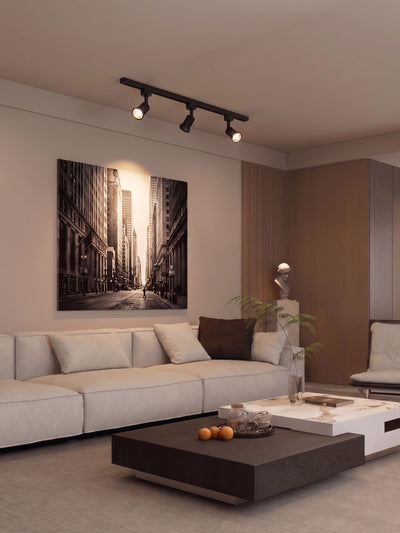 3 matte black track heads lighting living room artwork and plants